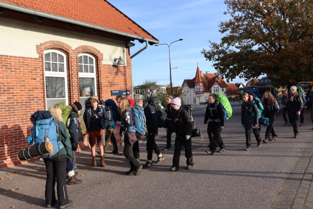 Kursister med rygsække går samlet gennem en by