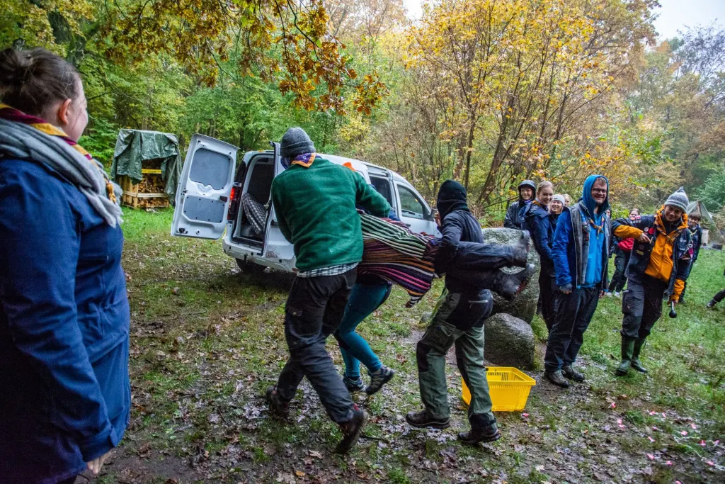 Vejledere bærer en kursist væk under en leg i skoven