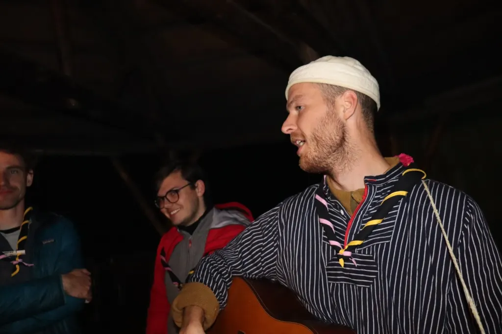 Vejleder spiller guitar ved lejrbålet om aftenen