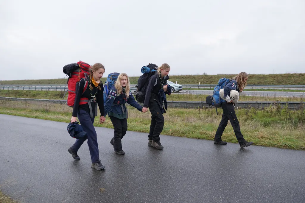 Spejdere med rygsække på vej gennem gråvejr